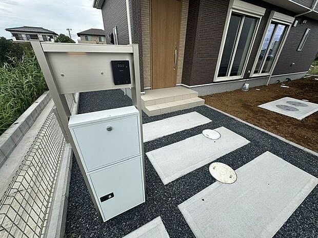 【機能門柱/1号棟】ポストやインターホンなどがまとめて設置された機能門柱。玄関先がすっきりと整い、統一感のある外構を演出します。