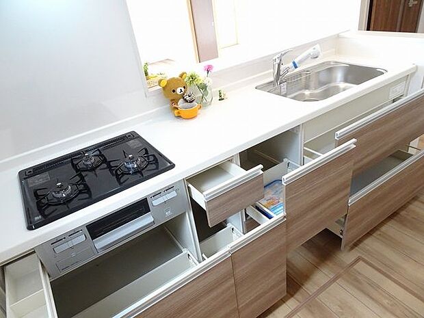 【キッチン/同仕様】グリル付きの三口ガスコンロが搭載されたシステムキッチン。下部の収納は使い勝手の良いスライド式です。※実際とは異なる場合があります。