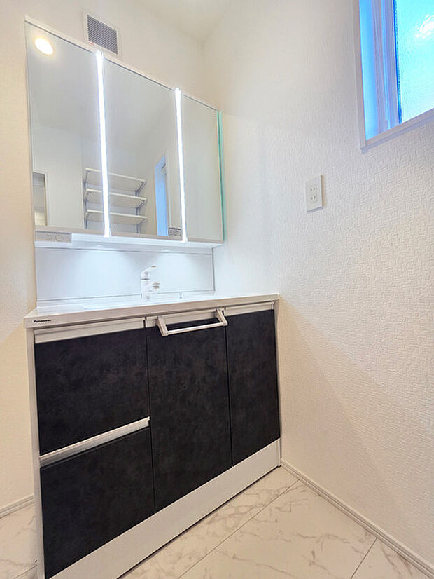 ゆとりの洗面スペースで朝の身支度も快適スムーズに。三面鏡で髪のセットやお化粧もストレスなくこなせ、朝から気分上昇！ 三面鏡の背面とシンク下の収納もたっぷり！アメニティ類のストックもバッチリ！ 