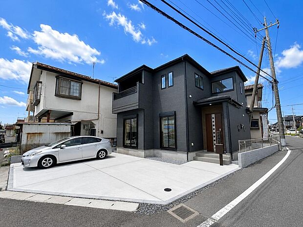 前面道路から建物全体を確認できます。駐車スペースや外構の様子も分かりやすい写真です。