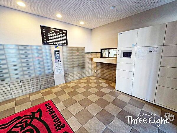 エントランス扉をくぐると、各種設備がお出迎え！中でも魅力的な設備が、画面右側に映る宅配ボックス♪ご不在時でも荷物の受け取りをすることができ、気兼ねなくネットでのお買い物が楽しめます！