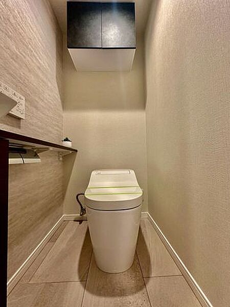 清潔感のあるタンクレストイレを採用したスマートな空間です！上部にはトイレットペーパーなどを隠して収納できる便利な吊戸棚を設置。手洗い器や温水洗浄便座も完備し、心地よく使える仕様となっています♪