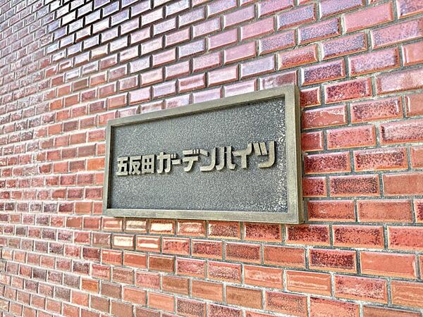 【エントランス】タイル壁に美しく映える、モダンなデザインのマンションサイン。
