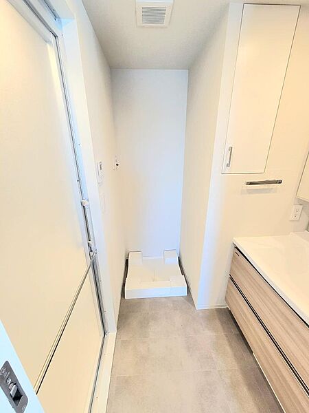 洗濯機置場を備えたゆとりある洗面室。三面鏡付き洗面化粧台と収納棚により、日用品やタオル類もすっきり整理できます。清潔感のある空間で、毎日の身支度や家事を快適にサポートします