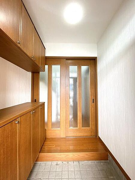 【リフォーム済】玄関ホールの写真です。壁・天井はクロスの張替えを行い、照明器具は新品に交換致しました。玄関はお家の顔となる部分、お客様が最初に目にする場所だからこそ、第一印象が大切ですね。