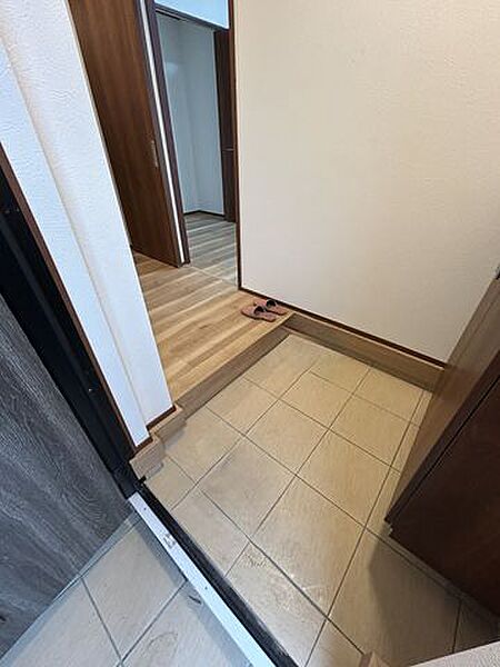 【リフォーム中】玄関ホール。床フローリング重ね張り、照明器具交換、天井・壁クロス張替でよりいっそう明るくなった玄関。家族の歴史を温かく見守ります。