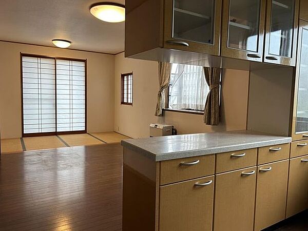 【LDK別角度】LDK北東側からの写真です。キッチン背面にカウンター付きの棚も設置されています。