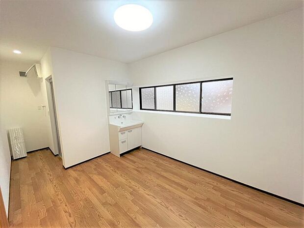 【リフォーム後】洗面脱衣所の写真です。床はクッションフロアを張り、天井・壁はクロスを張替えました。洗面台は新品に交換しました。