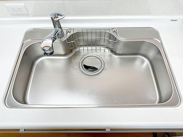 【リフォーム済】システムキッチンのシンクをクリーニングしています。水栓金具はシャワーホース内蔵タイプが設置されているのでお掃除のときや大きな鍋に水をためる時などに便利です。