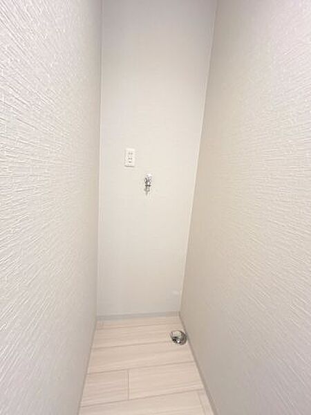 【リフォーム済】洗濯機置き場の写真。床クッションフロア張替、壁天井クロス張替行いました。蛇口は洗濯用水栓に変更、万が一ホースが抜けても水が流れない仕組み。