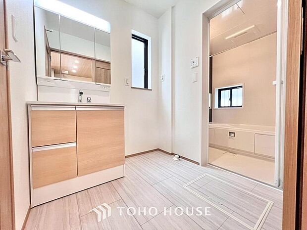 明るく清潔感のある洗面室には、機能的な三面鏡と使いやすい収納付き洗面台、洗濯機置場も備えています。