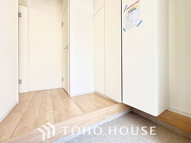 明るい光が差し込む広々とした新築戸建ての玄関です。毎日の出入りが楽しみになるような、清潔感にあふれた開放的な空間が広がっています。新生活の始まりを予感させる、洗練されたお住まいの顔を体感してください。