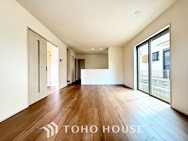 家族が集う一戸建ての広々としたリビング。大きな窓から明るい光が差し込み、開放感にあふれた空間です。家具の配置も自由自在で、家族団らんの時間を心地よく演出。家族の笑顔と会話が自然と弾む住まいの中心です。