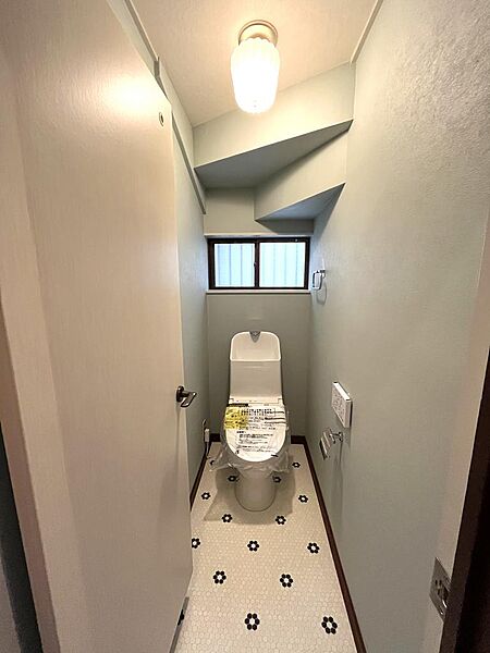 タイル調フロアと柔らかな照明が映える、デザイン性のあるトイレ空間。