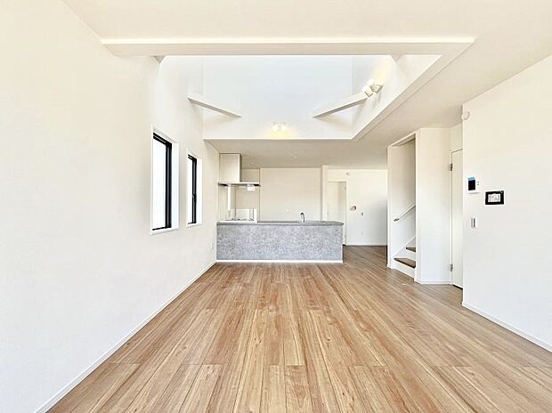 吹き抜けから明るい陽光が注ぎ、寛ぎの雰囲気に満たされるダイニング。