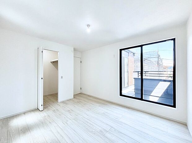 ウォークインクローゼット付きの洋室。バルコニーから入る明るい陽光が部屋全体を明るく照らします。