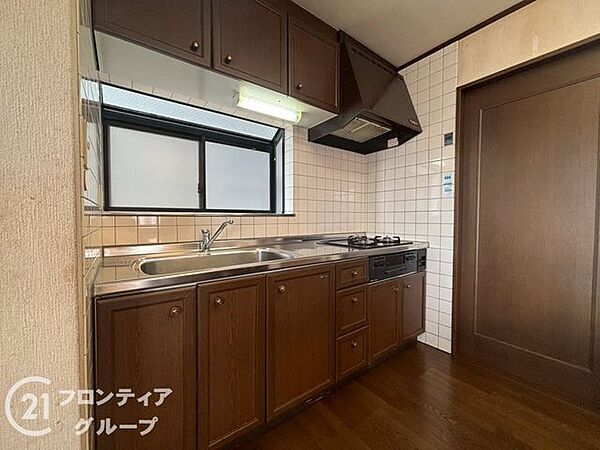 落ち着いた木目調のデザインが空間に溶け込むシステムキッチンです。正面に窓があるため、明るい光を感じながら心地よくお料理を楽しめます。収納スペースも豊富で、家事効率が向上する機能的な設計です