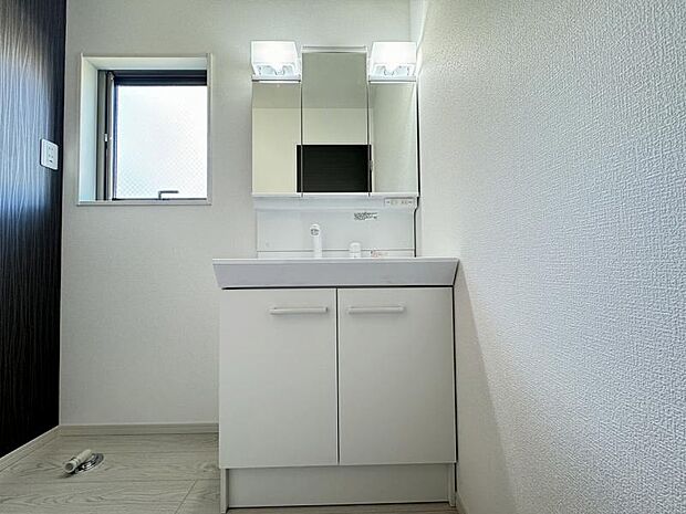 洗面台には三面鏡を採用。鏡の後ろに収納スペースが設けられています。