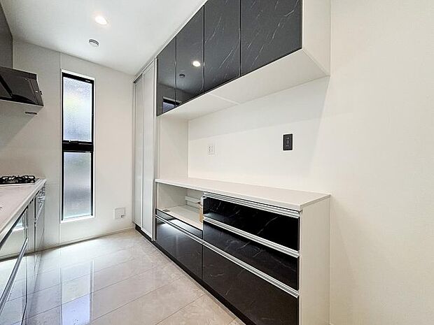 キッチンの背面に同色の面材を使用したカップボードを設置し、収納力と統一感を高めています。