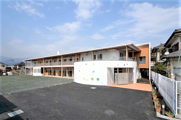 【愛歩保育園】510m 2010年4月に開設された新しい2階建ての園舎は、広い園庭を見渡すように建っています。園児さんが元気よく園庭を駈け回っています。