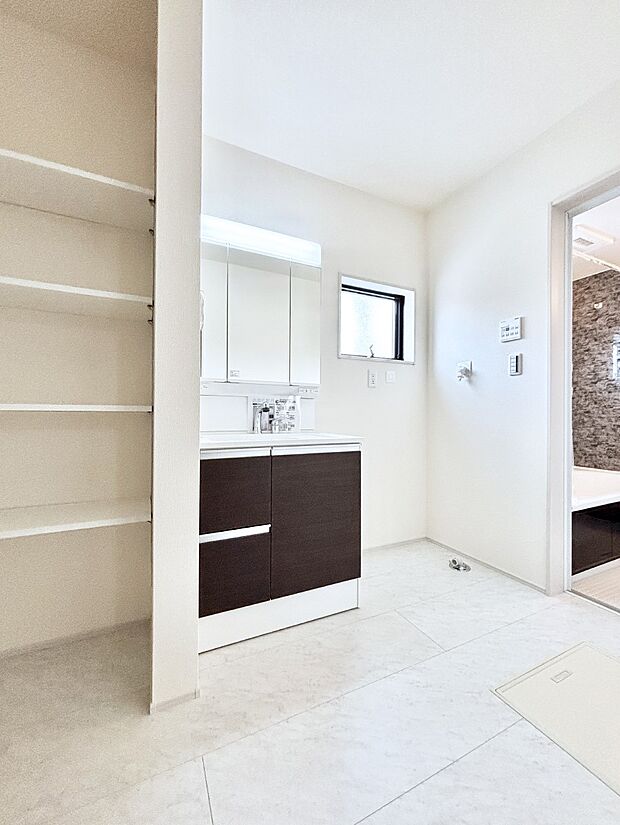 タオルや洗面用具のストック類を置ける便利な可動棚つきの脱衣場。