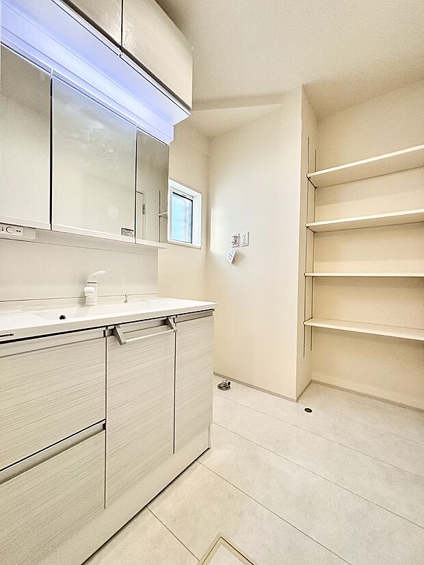 タオルや洗面用具のストック類を置ける便利な可動棚つきの洗面所。