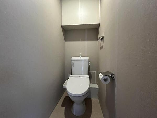 ～トイレ～ 上部に吊戸棚が設置された温水洗浄機能のトイレです。