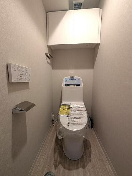 洗浄便座のトイレはスタイリッシュなデザイン、吊戸棚があり収納も安心