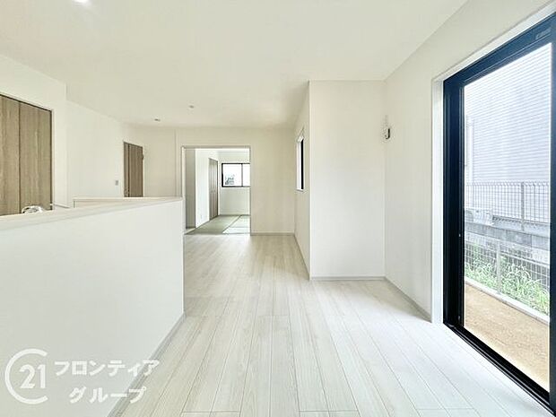 ナチュラルな木目調のフローリングと落ち着いたトーンのクロスが調和したリビング。大きな掃き出し窓が開放感を演出し、外の風景と心地よくつながります。家族との時間も一人の時間も楽しめる理想的な居住空間です。