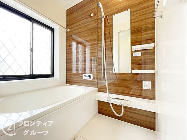 木目調のパネルが癒やしの時間を演出するバスルームです。一日の疲れをリセットするのにふさわしい清潔感あふれる落ち着いた空間ですね。足を伸ばしてゆったりとくつろげる広さがあり、毎晩の入浴が楽しみになります