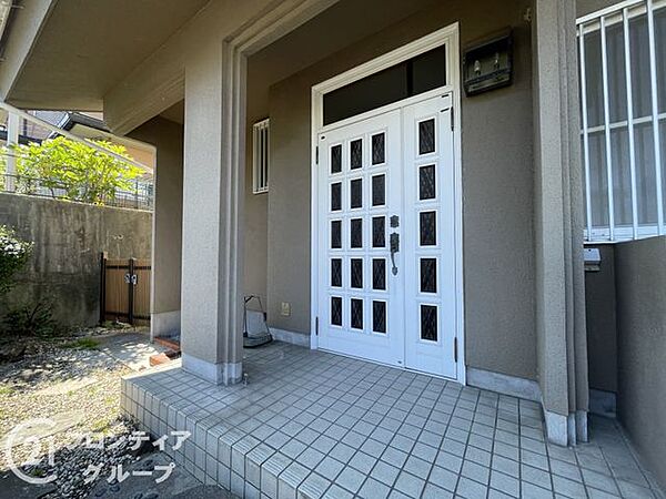 白を基調とした清潔感あふれる玄関扉が、訪れる人を明るく迎え入れます。ポーチ部分も広々としており、ベビーカーの出し入れや雨の日の出入りもスムーズに行える機能的な設計が施されています