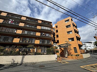 外観：オレンジ色のタイル貼りの外壁が街並みに映えるマンションです。多角的なデザインが特徴的な外観で、周囲の風景に溶け込みながらも存在感を放ちます。