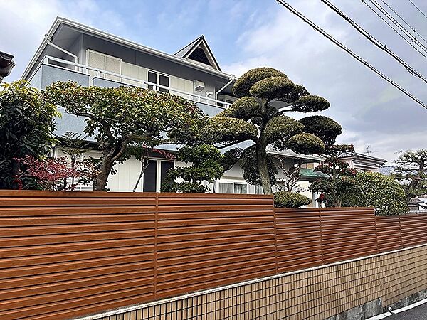 プライバシーに配慮された木目調のフェンスが魅力。手入れの行き届いた植栽が、住まいに彩りを添えます。