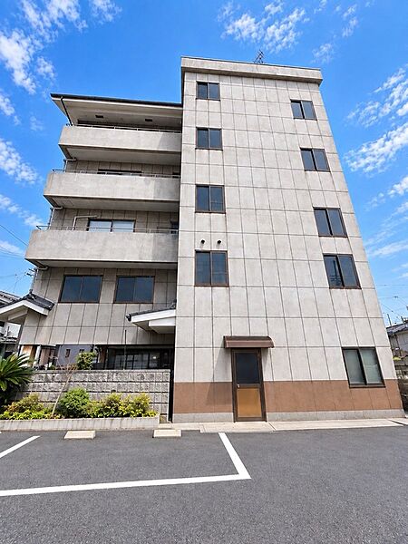 青空の下、堂々たる佇まいを見せる建物。広々とした駐車場も備え、ゆとりのある暮らしをサポートします。