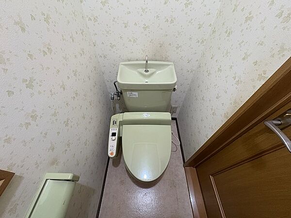 淡いリーフ柄のクロスとアースカラーのトイレが落ち着いた空間を演出。上部には手洗い器も備え、快適にご利用いただけます。