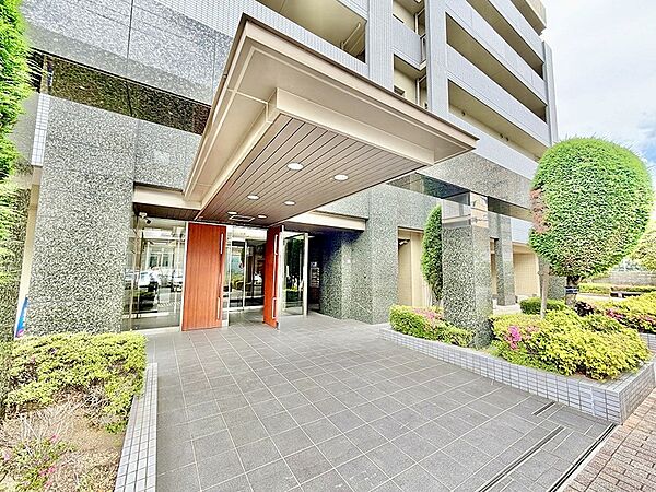 落ち着いた色合いの外壁が印象的なエントランス。植栽の緑が彩りを添え、穏やかな住空間へと誘います。