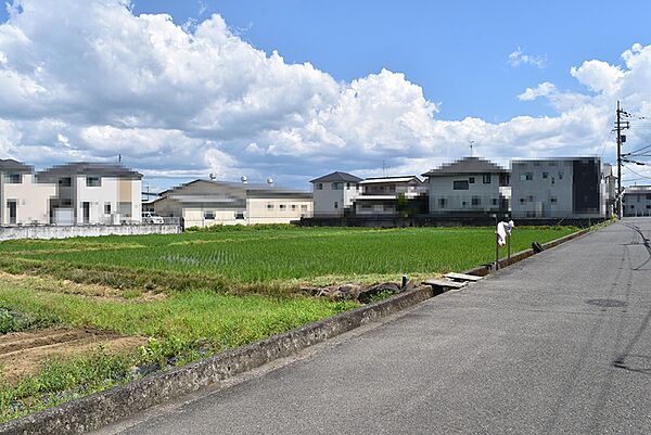 青空が広がる開放的な立地。周囲には住宅が立ち並び、住みやすい環境です。