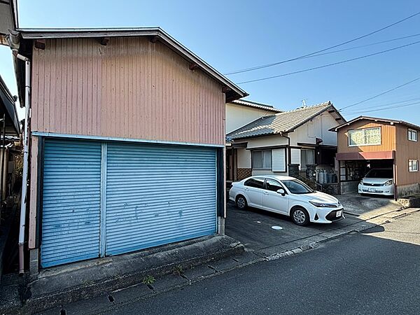 住居と車庫、倉庫が並ぶ穏やかな住宅地の一角。青いシャッターが印象的な建物は、趣味の空間としても活用できそうです。