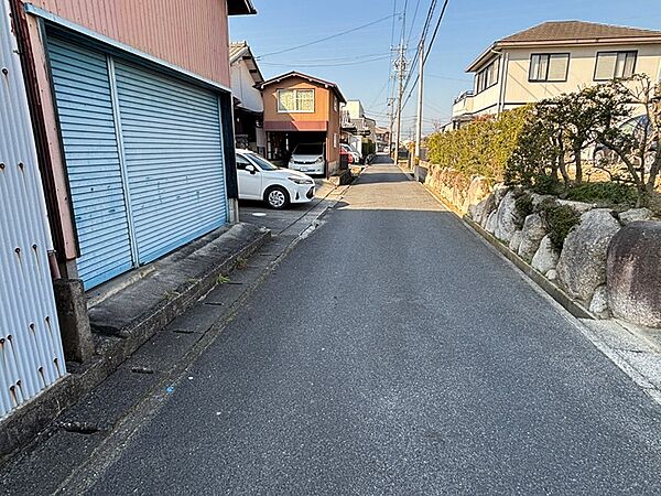 前面道路はアスファルト舗装で、閑静な住宅街に位置しています。穏やかな陽射しが差し込む明るい環境です。