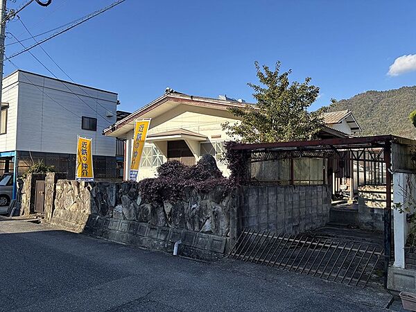 山々を望む閑静な住宅街の一画。平屋の物件には「近鉄の仲介」ののぼりが立ち、前面道路からアプローチしやすい立地です。