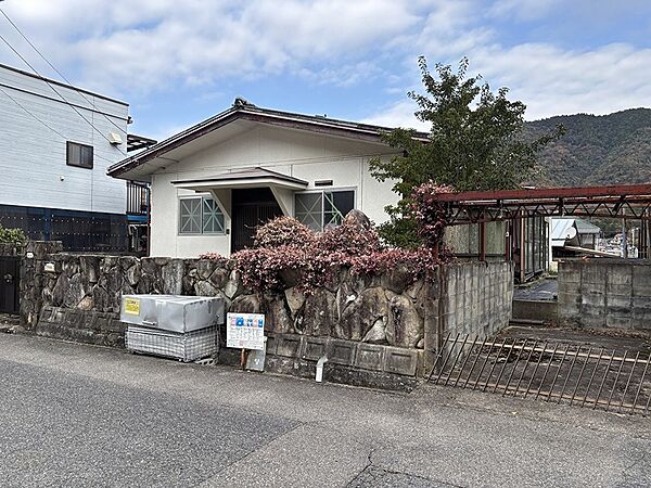 通り沿いに佇む一戸建て。住まいの雰囲気を演出する石積みの外壁と、手入れされた植栽が目を引きます。
