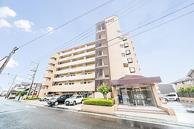 外観：明るい日差しが差し込む外観のマンションです。エントランスは落ち着いた色合いで、清潔感があります。