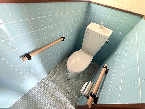 爽やかな水色のタイルと小石風の床が印象的なトイレ。手すり付きで、年齢を問わず安心して利用できます。日々の暮らしに心地よさをプラスします。