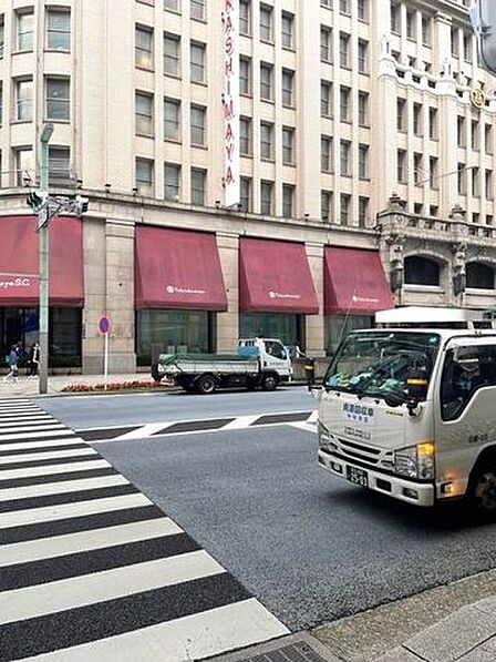 日本橋高島屋S．C．東館 重厚感のあるクラシカルなデザインの外観が特徴的な建物に面して舗装された道路があり、手前には横断歩道が設置されております。1階部分には赤いオーニングが並び、整然とした街並みが…