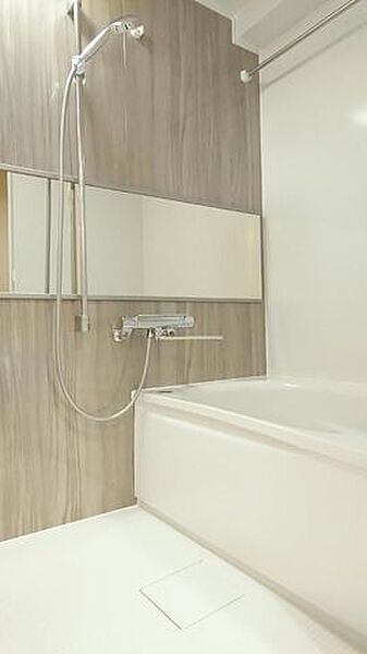 木目調のアクセントパネルが施された浴室には、横長のワイドミラーや高さ調節が可能なスライドバー付きシャワー、衣類干しに便利なランドリーパイプなど充実した設備が整っております。