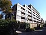 外観：グレーとブラウンを基調としたタイル張りの外壁が特徴的な外観で、各階にバルコニーを備えており、建物まわりには緑豊かな植栽と整備された歩道が配置されています。