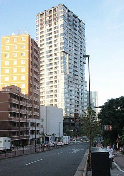 グレー調の外壁に多数のガラス面を組み合わせたスタイリッシュなデザインの高層マンション外観で、歩道やガードレールが整備された前面道路に面した立地となっております。
