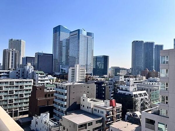 バルコニー側からの屋外景観であり、周辺に立ち並ぶ高層オフィスビルやタワーマンション群をはじめ、手前側に広がる中低層の建物や街並みを一望することができます。