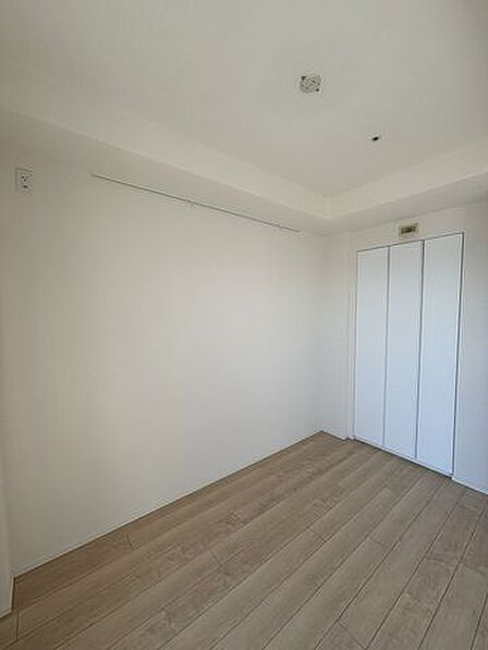 ナチュラルな木目調フローリングと白いクロスでシンプルに仕上げられた室内には、衣類や小物の整理に役立つ折れ戸付きのクローゼットと、壁面にピクチャーレールが設置されております。