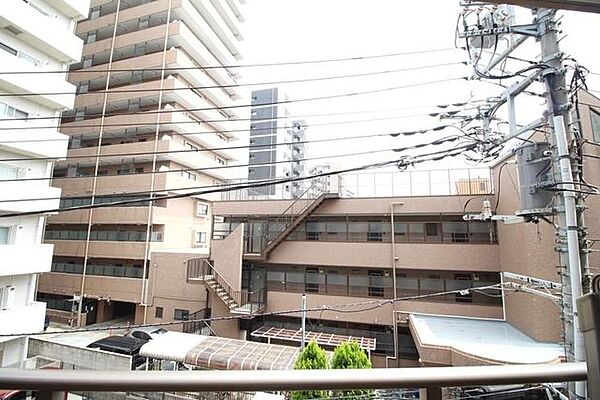 バルコニーの手すり越しからは、落ち着いたブラウン調の周辺マンションや外部階段、駐車場スペースなど、周辺の建物が見渡せる屋外の景観となっております。